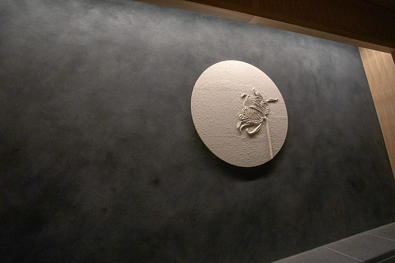 エレベータホールの壁には菊の花のレリーフが飾られている。1階はつぼみで上階では開花しているという演出