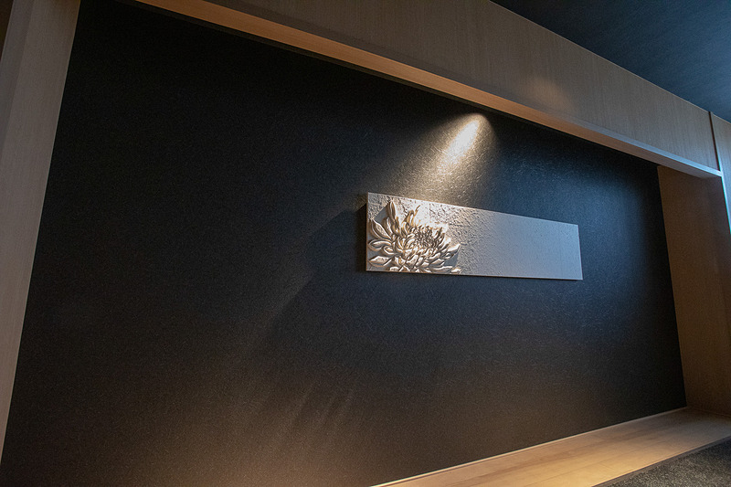 エレベータホールの壁には菊の花のレリーフが飾られている。1階はつぼみで上階では開花しているという演出