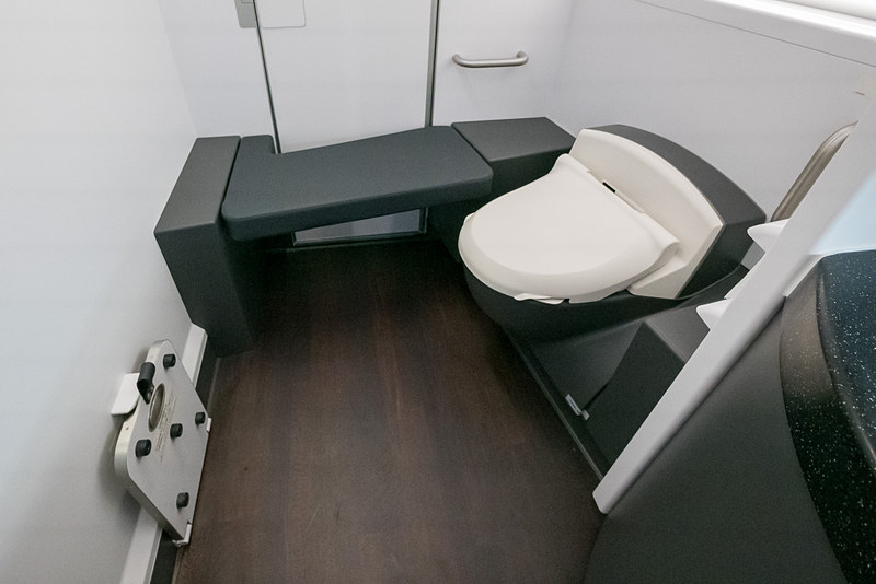 洗面台とトイレスペースがはっきり分かれ、ベンチシートや着替え台を備える広々としたラバトリー