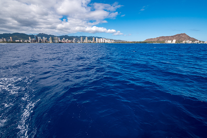 “エメラルドグリーンの海”とはまったく違う、沖から見る独特の青い海。遠くにマウイ島が見える（写真右）