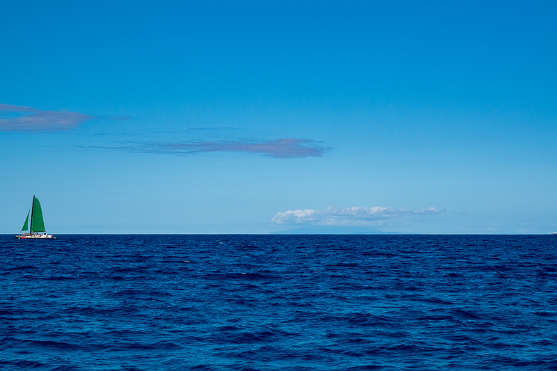 “エメラルドグリーンの海”とはまったく違う、沖から見る独特の青い海。遠くにマウイ島が見える（写真右）