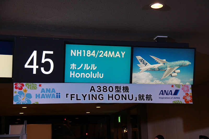 搭乗者をゲートで迎え一礼する平子社長と石田成田空港支店長。ディスプレイにはラニの画像も表示。フライト時間は7時間20分、現地は曇り、気温は23℃（摂氏）と表示されていた