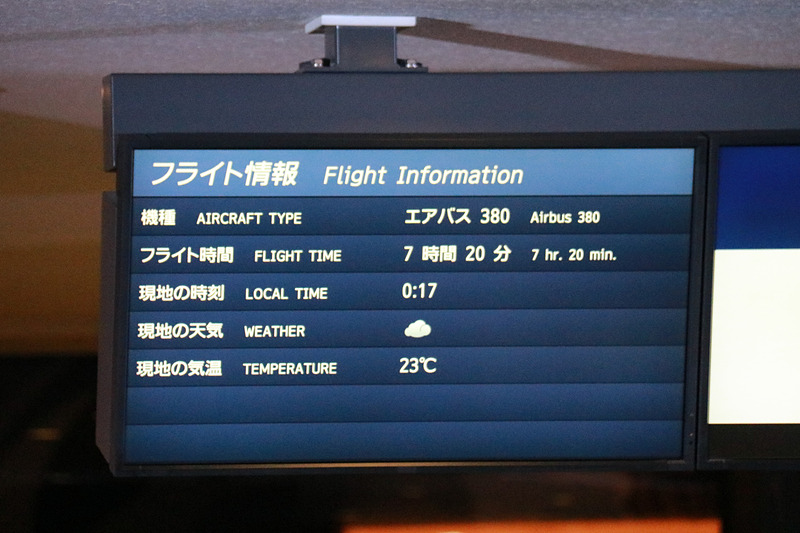 搭乗者をゲートで迎え一礼する平子社長と石田成田空港支店長。ディスプレイにはラニの画像も表示。フライト時間は7時間20分、現地は曇り、気温は23℃（摂氏）と表示されていた