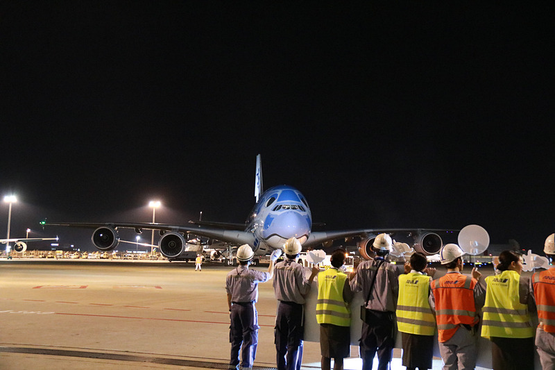 ラニのエンジンの向こうに見えるのは、FLYING HONU 2号機のカイ。機長が地上の見送りに向かい手を振ってプッシュバック。トーイングカーにもメッセージが貼られていた