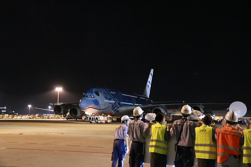 ラニのエンジンの向こうに見えるのは、FLYING HONU 2号機のカイ。機長が地上の見送りに向かい手を振ってプッシュバック。トーイングカーにもメッセージが貼られていた