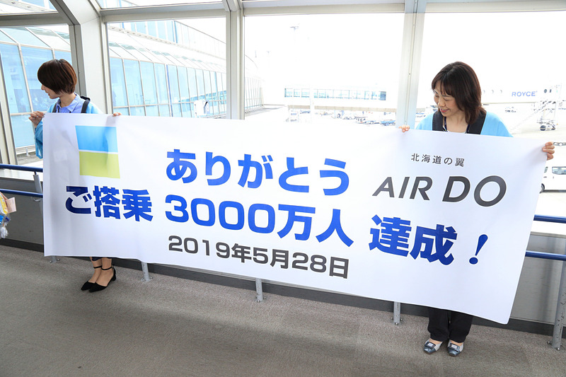 3000万人達成を記念した横断幕と、お菓子をプレゼントした谷寧久氏、グランドスタッフ、CA、そしてベア・ドゥ