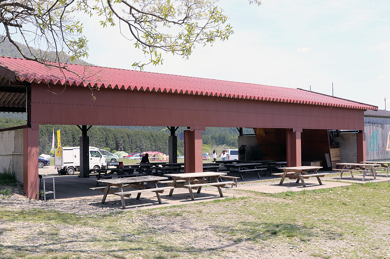 椅子とテーブル、自動販売機、水場などを備える屋外キッチン