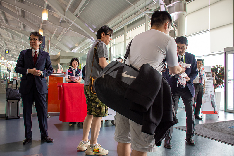 阿部孝博氏らがゲート前で乗客一人一人に笑顔で記念品を手渡した