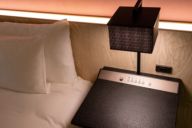 ベッドサイドテーブルには照明の操作パネルが控えめに。電源コンセントも