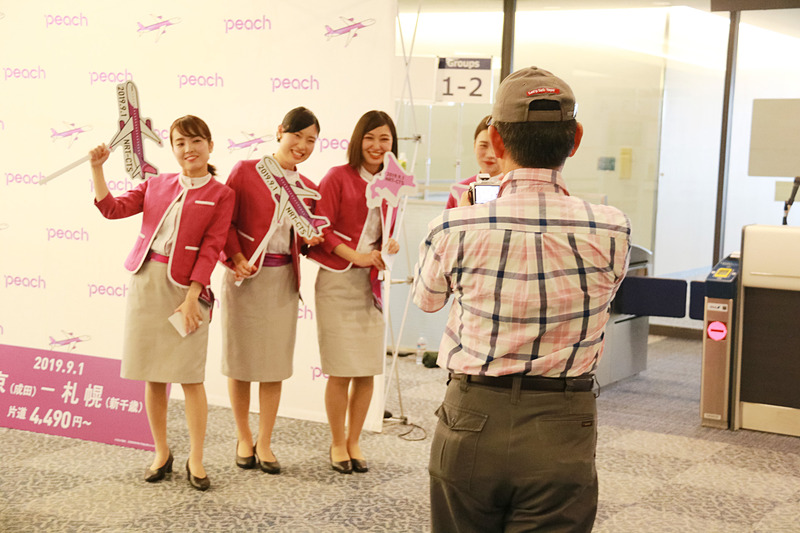 初便搭乗客に記念ステッカーをプレゼントしたり、一緒に記念撮影をするCAたち