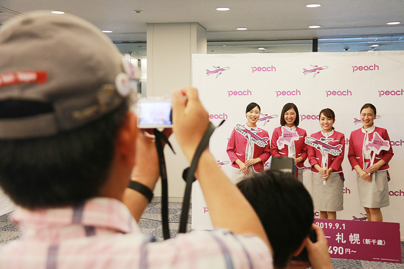 初便搭乗客に記念ステッカーをプレゼントしたり、一緒に記念撮影をするCAたち