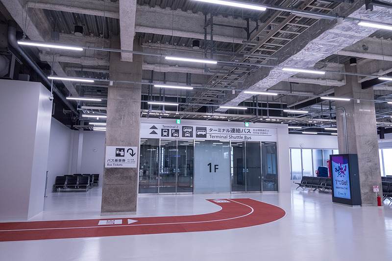 出口の先に拡張された到着ロビー。赤いマットで示されたルートに沿って進むと、出発ロビーを経由せずに屋外へ。そのまま、第3ターミナルの入口に行くことができる。また従来のようにエスカレータやエレベータ、階段を使って2階出発ロビーへ行くことも可能で、この階段は従来は禁止されていた2階から1階への移動も可能になる
