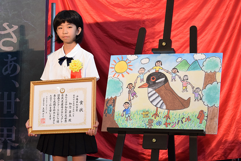 知念さんの作品は、ヤンバルクイナを中心に子供たちが手をつないで囲んでいる様子を描いている