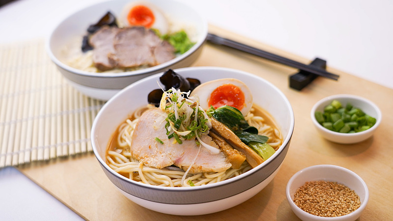 シンガポール航空の機内で10月1日から「けいすけラーメン」を提供。写真はファーストクラスで提供する「けいすけロブスターラーメン」（手前）と「けいすけ豚骨ラーメン」（奥）