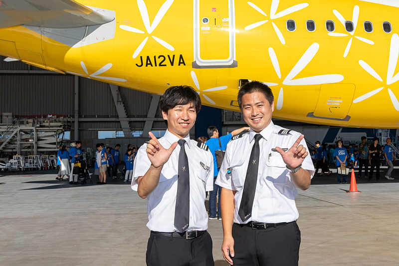 機体の前でピースサインのパイロット