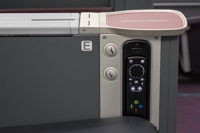 サイドテーブルの下に、機内エンタテイメントサービスのコントローラと、リクライニング/フットレストのロック