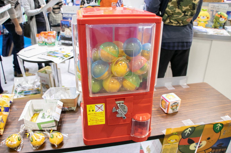 お笑いコンビ「和牛」のポスターが目を引く愛媛県は、みかんがカプセルに入ったガシャポン企画を実施中