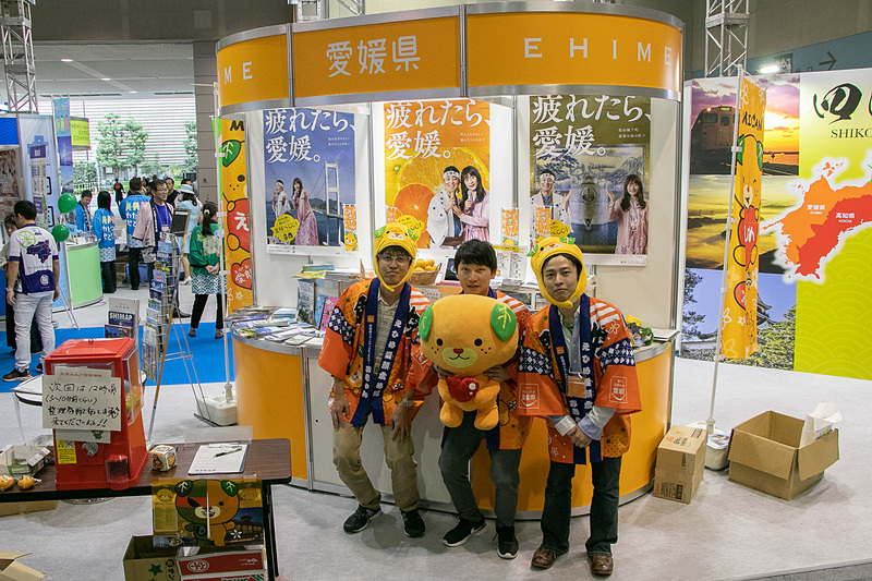 お笑いコンビ「和牛」のポスターが目を引く愛媛県は、みかんがカプセルに入ったガシャポン企画を実施中