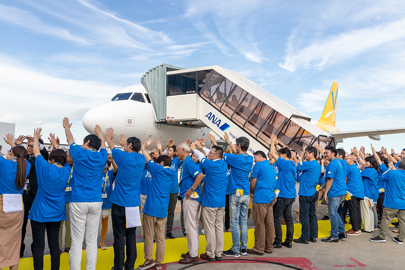 飛行機の前では社員の人間アーチで乗客をお出迎え