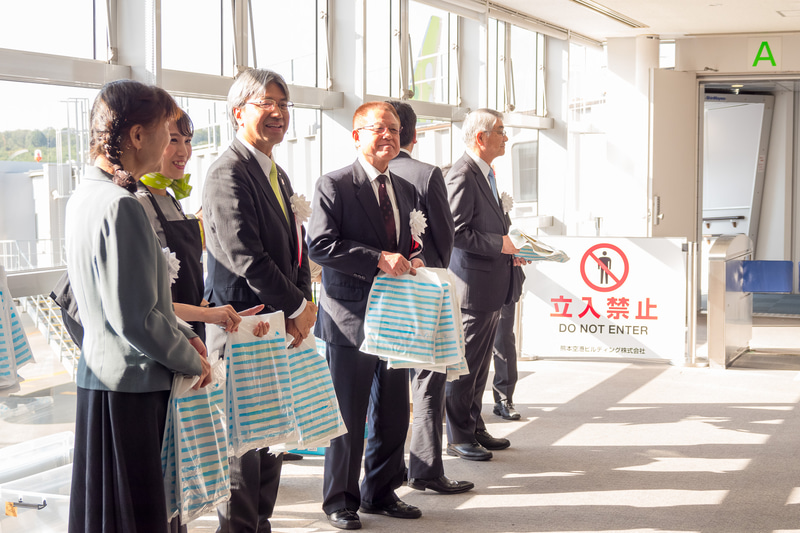 関係者が並んで搭乗客一人一人に記念品をプレゼントした