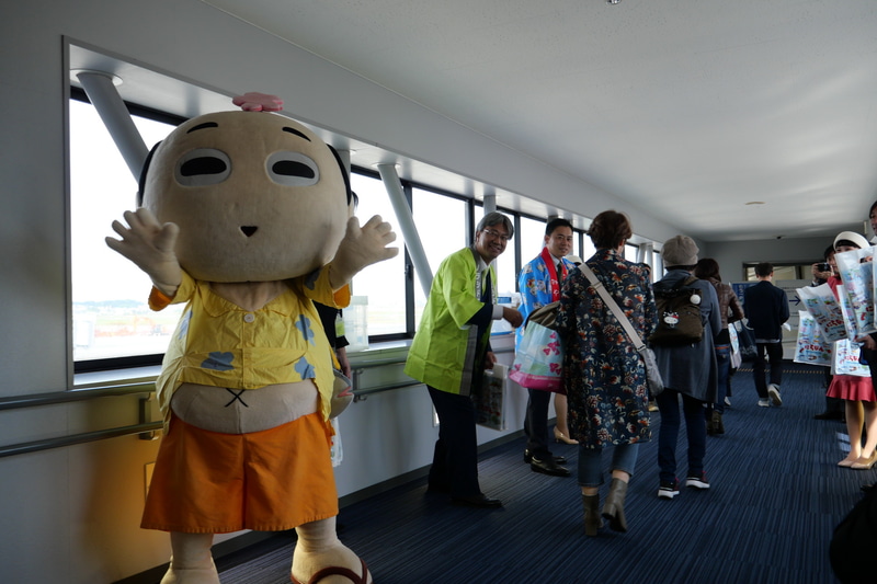 セレモニー参加者が搭乗口に並び、乗客に記念品をプレゼントした