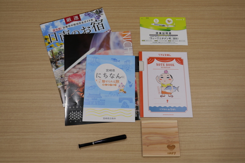 ウィーラブニチナン号の搭乗証明書とともに、日南市の観光ガイド、「ウィーラブニチナン」のロゴを彫り込んだ木製コースター、バット型ボールペンにダイアリーノートなどがプレゼントされた
