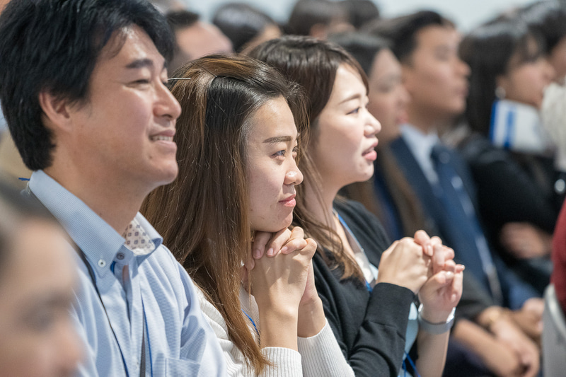 同僚のパフォーマンスを祈るような表情で応援する姿も