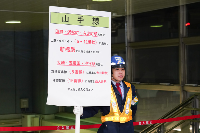 乗り換えの案内を持つ警備員が配置された