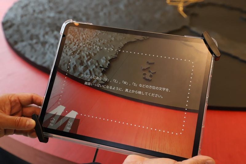 モノトーンのジオラマを撮影しているが、画面上にはカラーCGが表示される