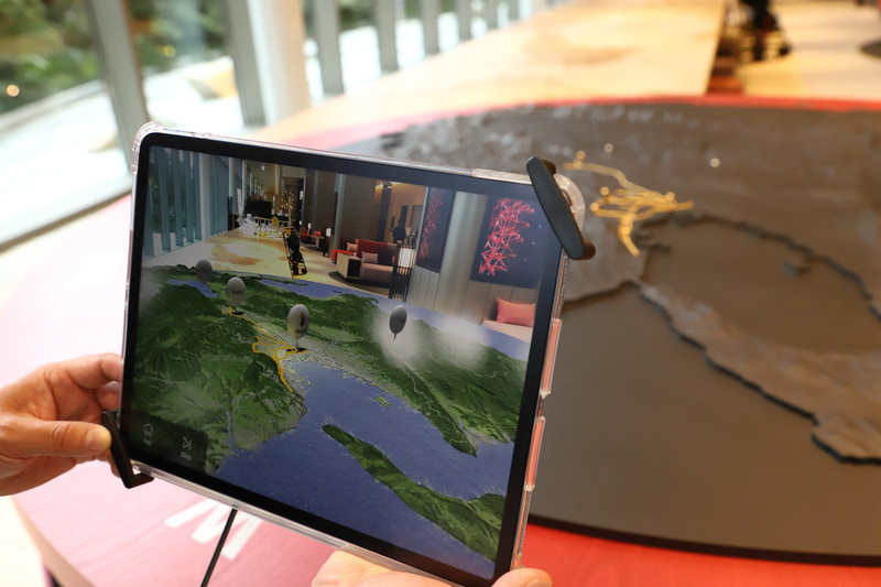 モノトーンのジオラマを撮影しているが、画面上にはカラーCGが表示される