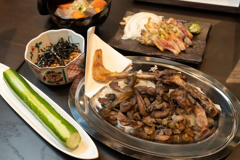 名物の「薩摩地鶏もも焼き」。後ろにあるのは「鶏刺し」