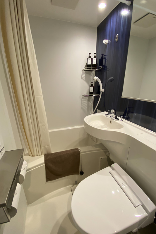 バスルーム。広角撮影で強調されているが、広さは1ルームマンションのユニットバス程度