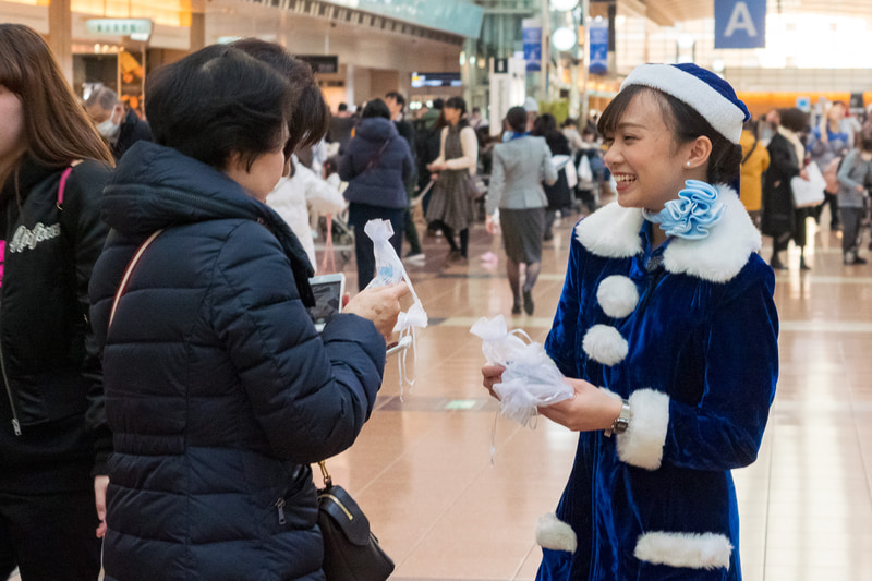 空港利用者にクリスマスプレゼント。ステッカーやクリスマスタグ、チョコレートをプレゼントした