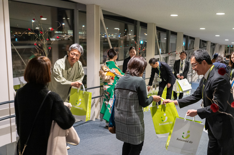 髙橋社長らが搭乗客に記念品を手渡し