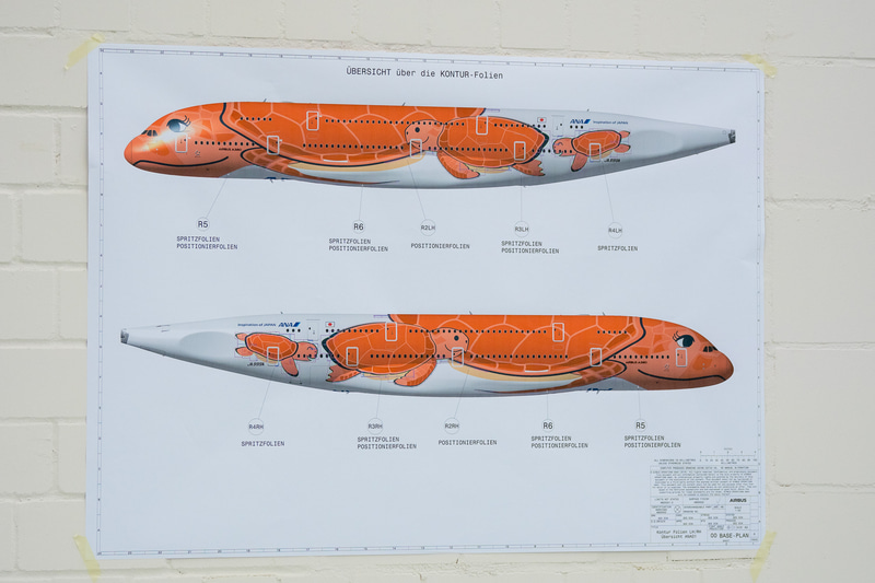 塗装工場内。ステンシルを制作する部屋には、初号機がロールアウトした際に使われたANAの旗が飾られていた