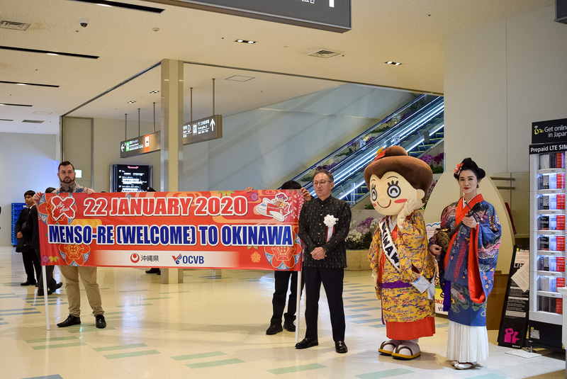 歓迎の横断幕。玉城デニー沖縄県知事も出迎えに並ぶ