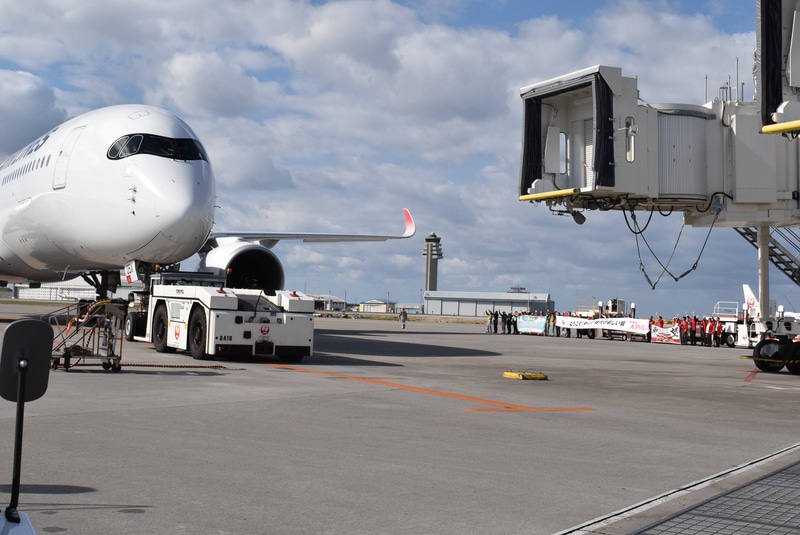 スポットを離れるA350型機。向こうではJALグループ関係者が横断幕を掲げている