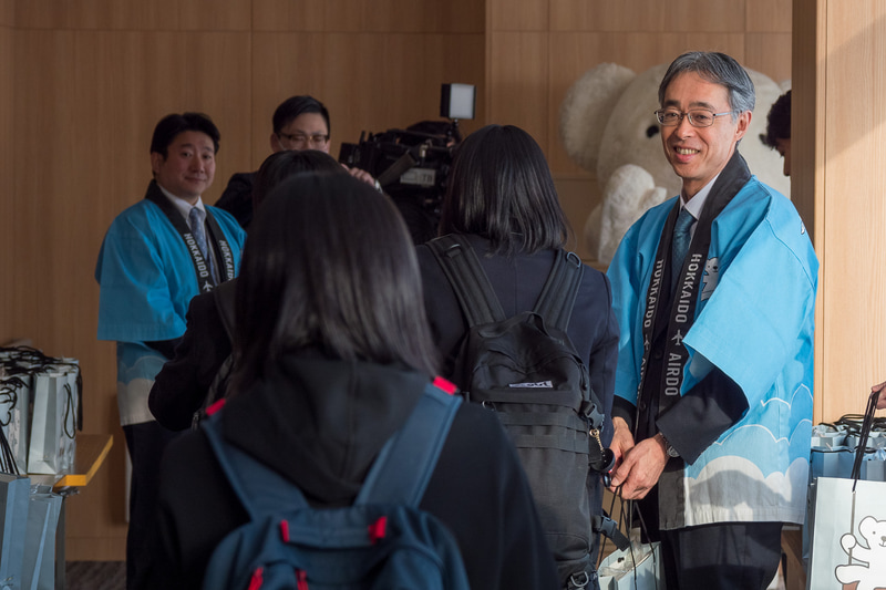 株式会社AIRDO 代表取締役社長 草野晋氏（左上）らが記念品を配布するとともに搭乗客をお見送り