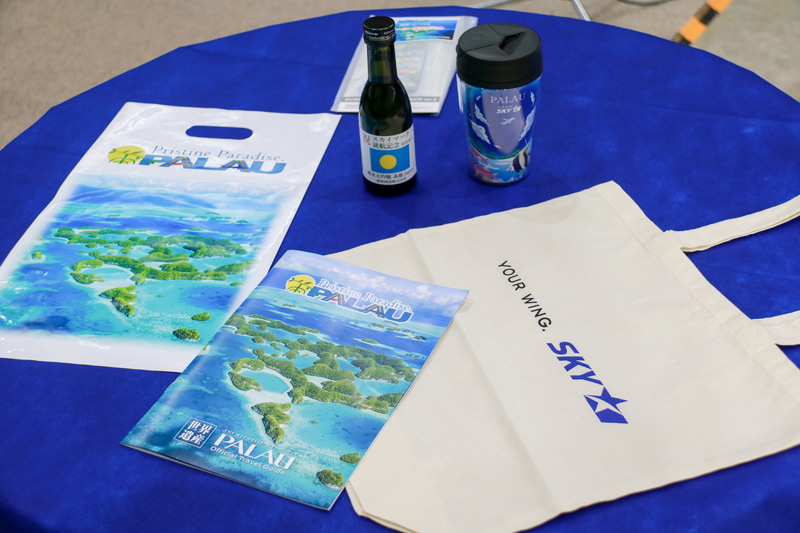 佐山会長、田中美奈子さん、フランシス・マツタロウ氏たちが搭乗ゲートで記念品の配布を行なった