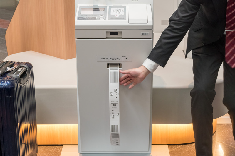 自動チェックイン機でのタグ発行から自動手荷物預け機への流れを、日本航空株式会社 空港企画部 旅客・制度企画グループ 主任 槇裕作氏がデモ。具体的な手順は後述する