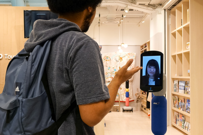 案内所を訪れた外国人をnewmeが出迎え、遠隔地にいるスタッフが接遇