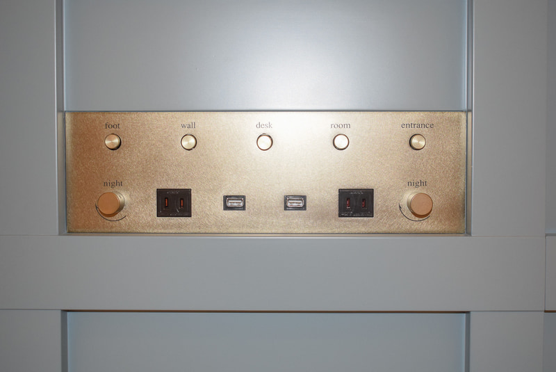 枕元に電源コンセントとUSB充電ポートを設置。写真の電源パネルの2口のほかに増設ベッド用に2口備えており、4人で泊まっても1人1口使える