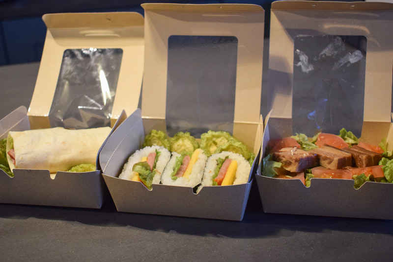 ラップサンド、スパムおにぎり、タコライスなどの軽食も用意。持ち運びしやすいようにボックスに入っている
