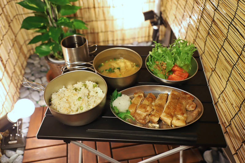 チキンソテーと豆ごはんの夕食。ご飯とみそ汁とお茶はチタンのアウトドアクッカー、ソテーとサラダは100円ショップのアルミ皿だが違和感なくまとまった。左にご飯とみそ汁を置くのは関西では一般常識だ