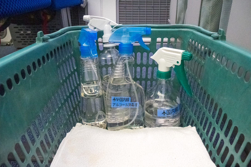 この日の最終運航を終えた機体へと進む清掃スタッフ。手にはアルコール消毒液とクロスの入ったカゴが