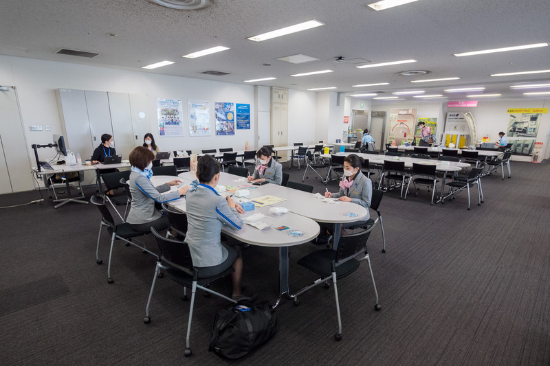 乗務前のCAがブリーフィングを行なうテーブルの消毒。もともと机2個をつなげて6か所設けていたが、ソーシャルディスタンス確保のために机4つをつなげた3エリアにレイアウト変更した