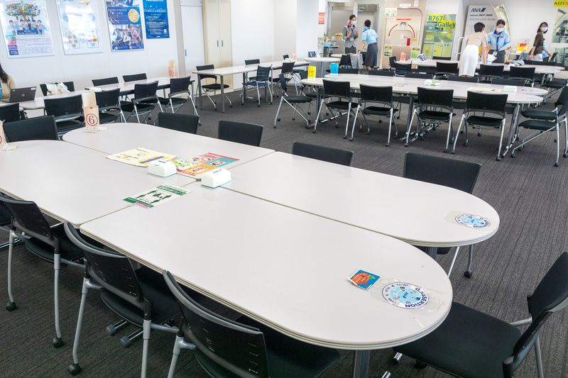 乗務前のCAがブリーフィングを行なうテーブルの消毒。もともと机2個をつなげて6か所設けていたが、ソーシャルディスタンス確保のために机4つをつなげた3エリアにレイアウト変更した