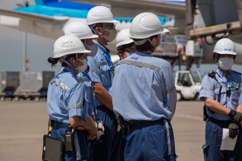 到着前にチームで集まってミーティング。日焼け防止のために長袖制服を着用するスタッフも多い
