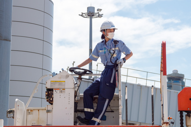 貨物を下ろす作業が進められる。ソーシャルディスタンスが確保できる屋外作業では、熱中症対策のためにマスクを外すことを推奨している