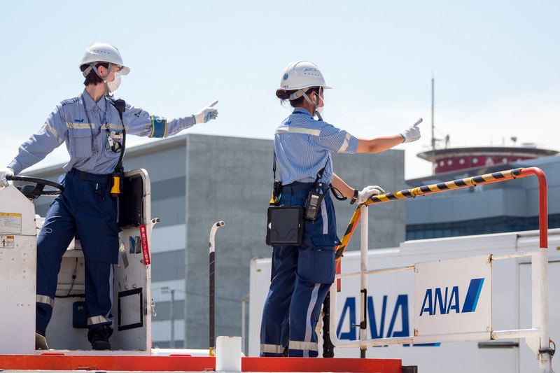 貨物を下ろす作業が進められる。ソーシャルディスタンスが確保できる屋外作業では、熱中症対策のためにマスクを外すことを推奨している